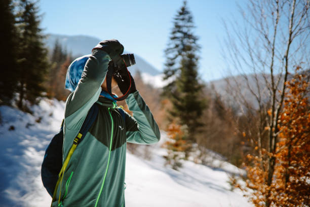 Man stopping to take a shot with his camera, while snowshoeing in the beautiful outdoors.