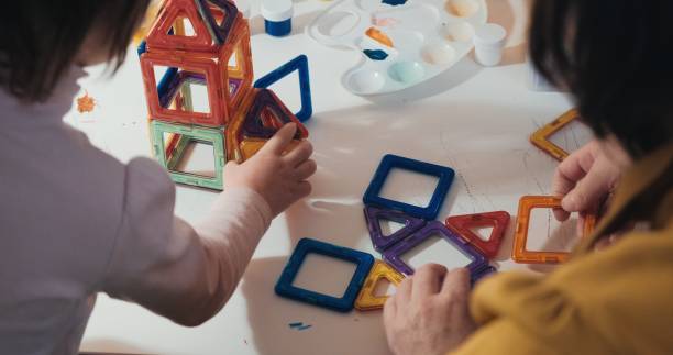 istock Child with his mother collects a magnetic constructor, close up shot, rear view 1383621749