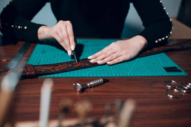 istock Embossing Cerving Stamping Tooling Modeling Kiridash Leather. Tanner woman making leather bag belt pattern with kiridashi knife on workshop. 1383621833