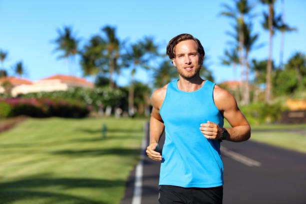 Running athlete man runner training cardio on road for marathon run. Athletic fit young sport fitness model outside in tropical summer city Running athlete man runner training cardio on road for marathon run. Athletic fit young sport fitness model outside in tropical summer city. miami marathon stock pictures, royalty-free photos & images