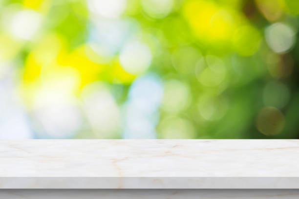 istock Marble table top with blur green leaf bokeh nature background 1383621894