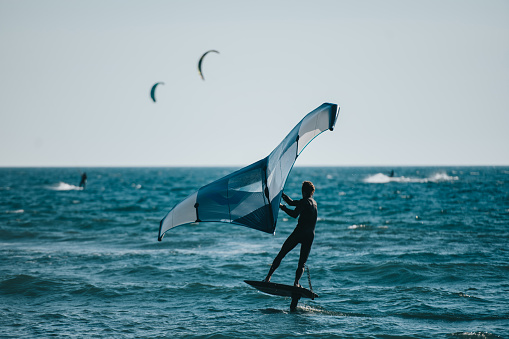 Aerial view photo of a young man windsurfing on the open sea. High angle view. Drone point of view.