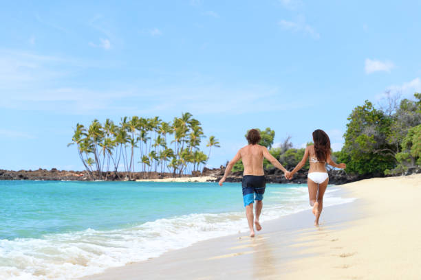 istock Happy couple holding hands on fun vacation beach 1383623211
