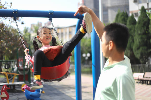 istock a father playing swings with his daughters. 1383625145