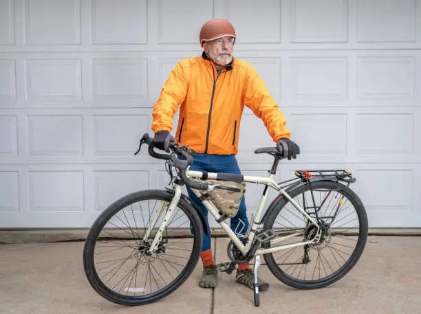 senior make cyclist standing with his touring bike in a driveway ready for a ride