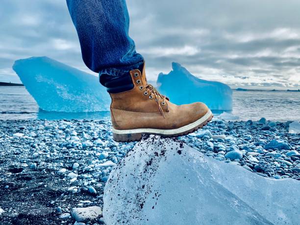 Yellow boot on an ice cube on rocky beach, Iceland