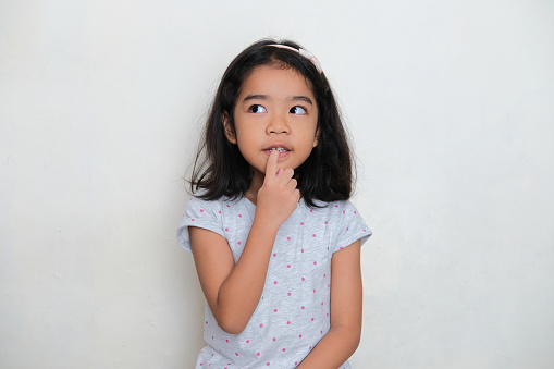 Asian kid showing thinking gesture while looking to the right
