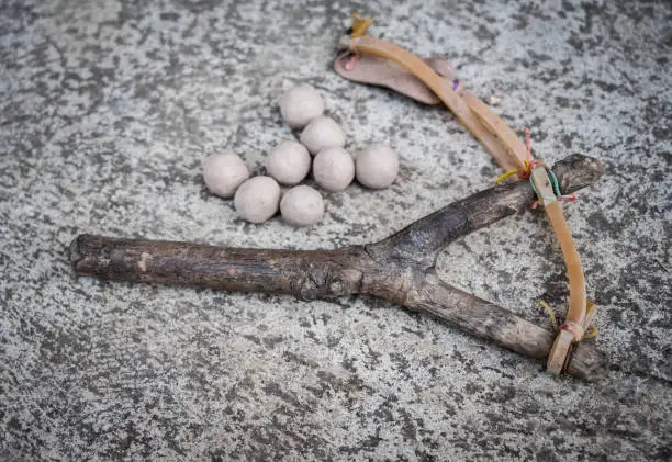 Photo of A wood slingshot with clay balls on the cement floor.