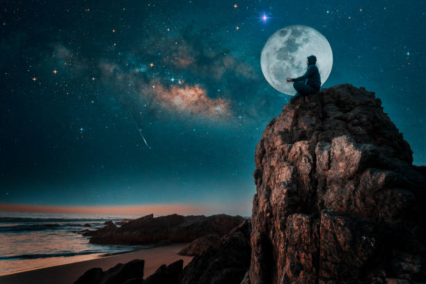 person silhouette sitting on the top of the mountain meditating or contemplating the starry night with Milky Way and Moon background person silhouette sitting on the top of the mountain meditating or contemplating the starry night with Milky Way and Moon background full moon stock pictures, royalty-free photos & images