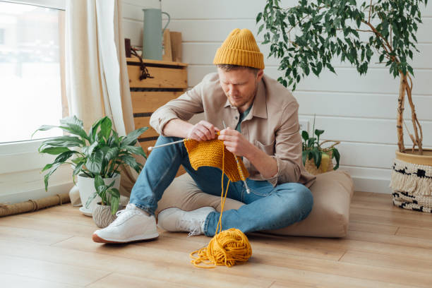istock Middle aged man learning knitting on needles. Knitting project in progress. Man learning a new hobby 1383645438