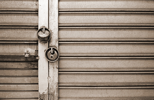 Black and white film image of a locked security gate in a  depressed section of city.