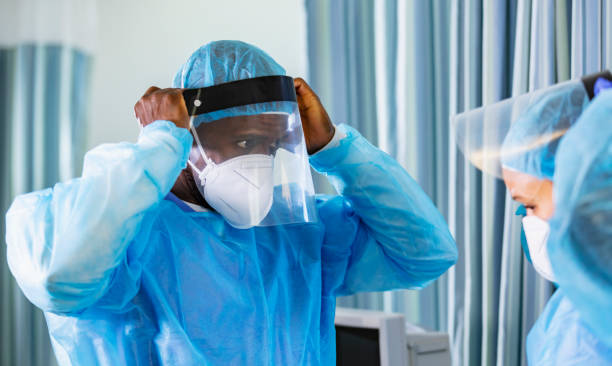 istock Two healthcare workers putting on PPE, face shields 1383692890