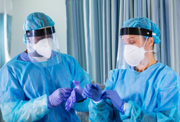 istock Two multiracial healthcare workers putting on full PPE 1383692951