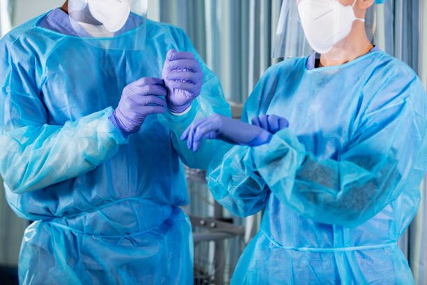 istock Two multiracial healthcare workers putting on full PPE 1383693012