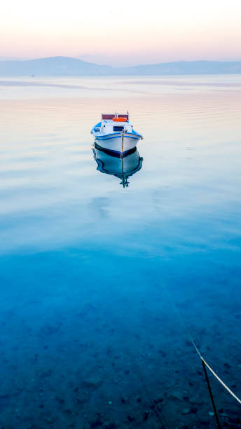 Lonely boat floating on the tranquil sea water, Ayvalik, Turkey stock photo