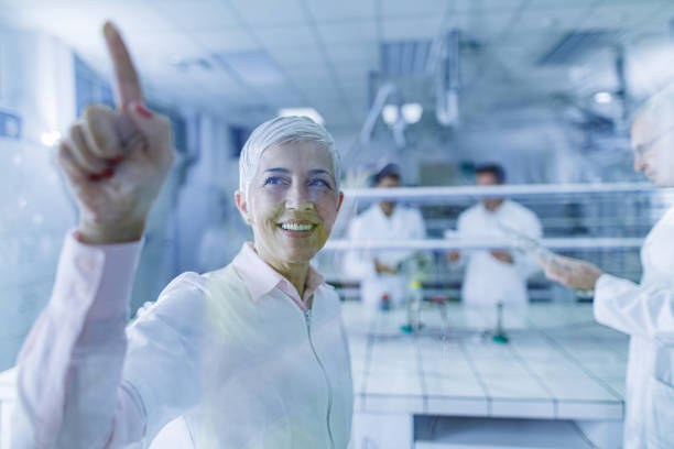 istock Happy mature chemist working on touch screen in laboratory. 1383723416