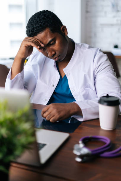 istock African American black man doctor looking at MRI brain scan image while working at desk with laptop 1383726629