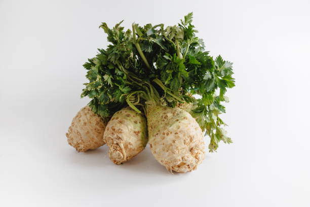 Group of celeriac roots with leaves on white background, organic food, studio shot