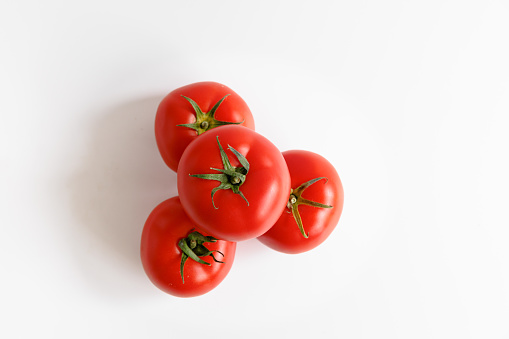 Small heap of red tomatoes on white background, organic food, studio shot directly above