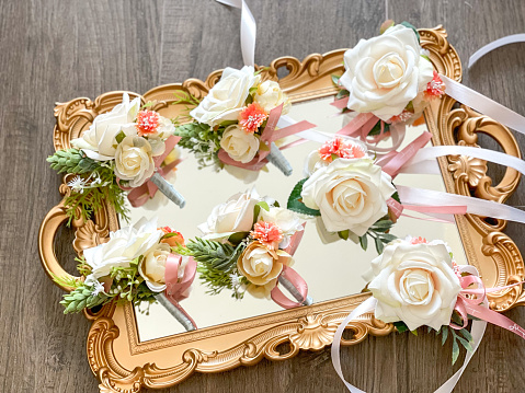 White roses groom corsage and boutonnière for wedding on a vintage golden mirror tray