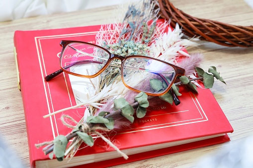 Glasses and dried flowers placed on top of the red album