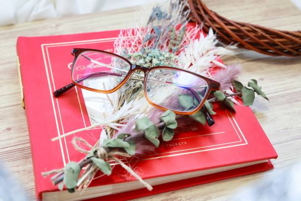 Glasses and dried flowers placed on top of the red album stock photo