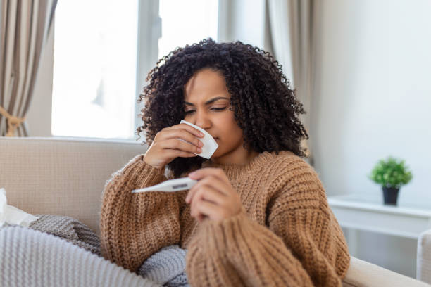istock Sickness, seasonal virus problem concept. Woman being sick having flu lying on bed looking at temperature on thermometer. Sick woman lying in bed with high fever. Cold flu coronavirus, covid19 1383752157