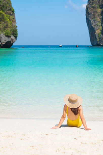 mulher turista de maiô amarelo e chapéu, viajante feliz tomando sol na praia de maya bay na ilha phi phi, krabi, tailândia. marco, destino sudeste asiático viagens, férias e conceito de férias - southeast asian ethnicity fotos - fotografias e filmes do acervo