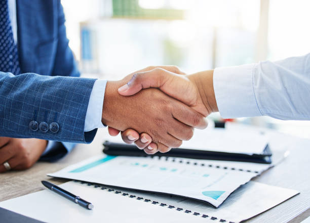 shot of two unrecognizable businessmen shaking hands in a office - win win imagens e fotografias de stock