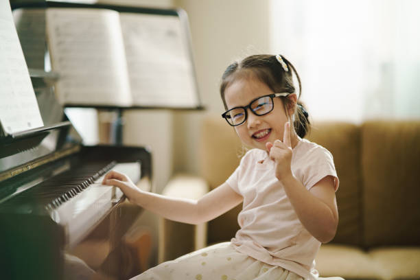 아시아 행복 유아 소녀는 피아노를 연주하는 동안 미소와 카메라 포인트 손가락을 보고, 악기, 공연, 유아 음악 교육, 레저 음악 악기 활동을 탐구. - skill piano music child 뉴스 사진 이미지