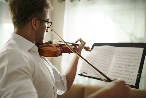 Scene of musician practicing violin in the music instrument room.