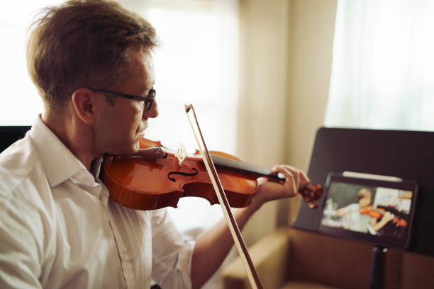 istock Scene of violin teacher teaching students by online music training or E-class learning while covid-19 spread out or crisis situation, Musician practice violin online together for social distancing 1383761053