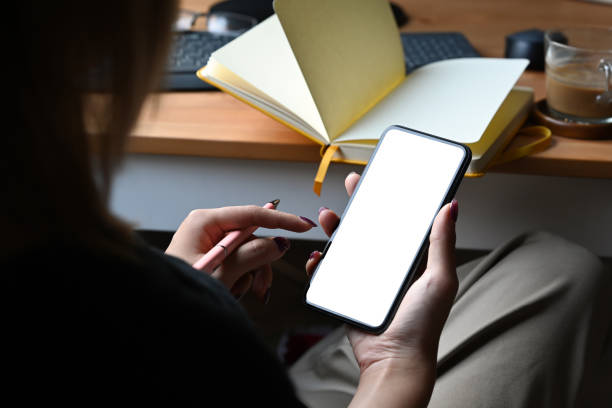 istock Over shoulder view woman sitting and her workplace and using smart phone. 1383770425