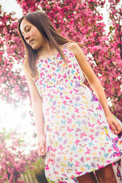 12 years old mixed race girl posing in front if cherry blossom tree.