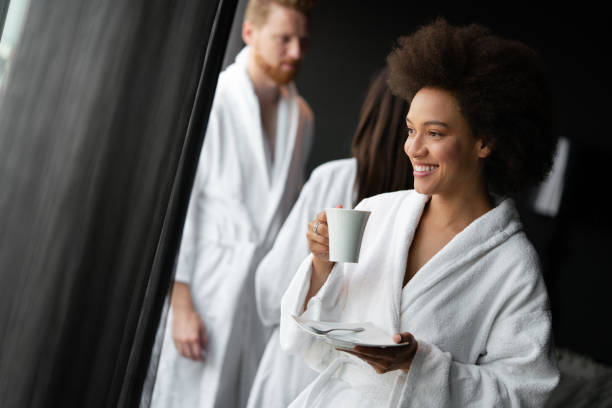 ritratto di una bella giovane donna che beve il tè vestita in accappatoio in un centro benessere spa - bathrobe women cup towel foto e immagini stock