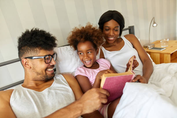 istock Happy family reading an interesting book in bed 1383793617