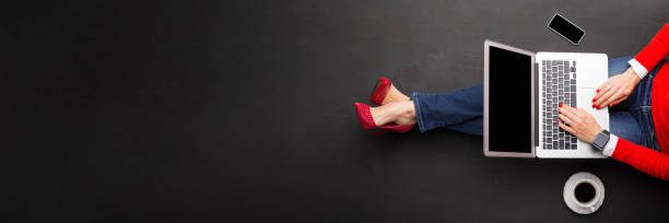Woman working with laptop on dark floor, view from above, banner size