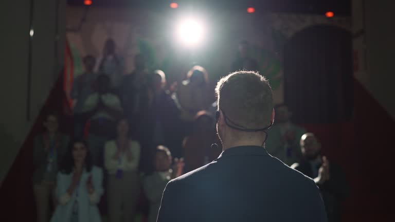 Rear view of a businessman entrepreneur giving a lecture to a crowd