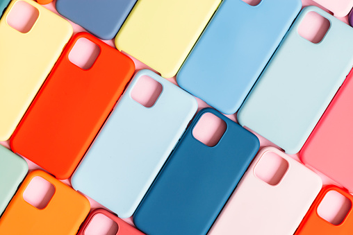 pattern of bright multicolored red blue and yeallow plastic smartphone cases over pink background