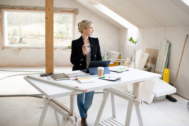 pretty young architect working on construction site in loft and standing by high table