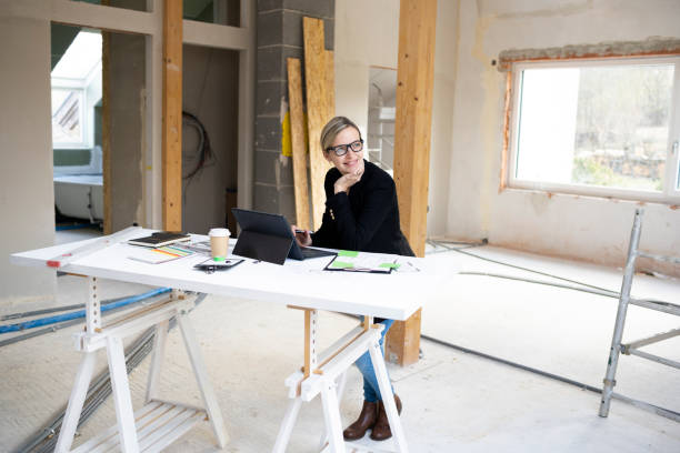 istock pretty young architect working on construction site in loft and standing by high table 1383814115