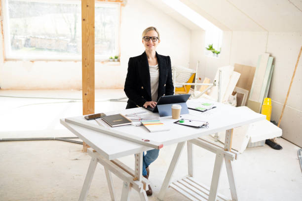 istock pretty young architect working on construction site in loft and standing by high table 1383814120