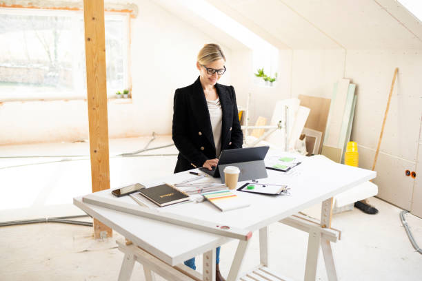istock pretty young architect working on construction site in loft and standing by high table 1383814134