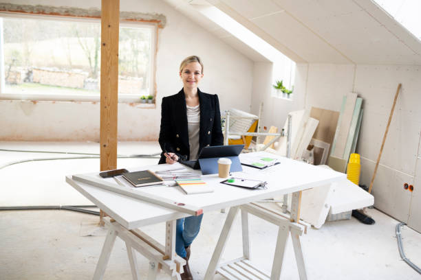 istock pretty young architect working on construction site in loft and standing by high table 1383814233