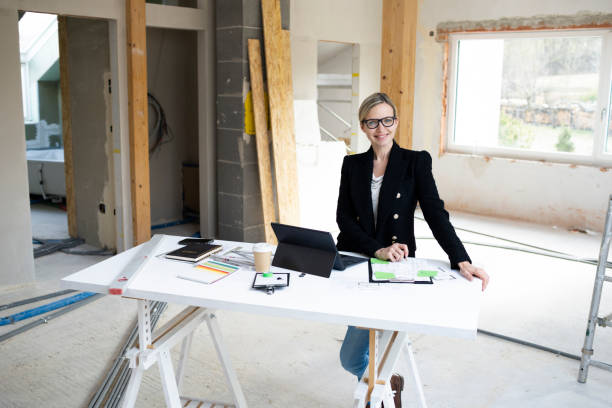 istock pretty young architect working on construction site in loft and standing by high table 1383814575
