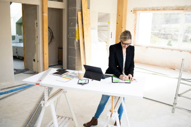 istock pretty young architect working on construction site in loft and standing by high table 1383814580