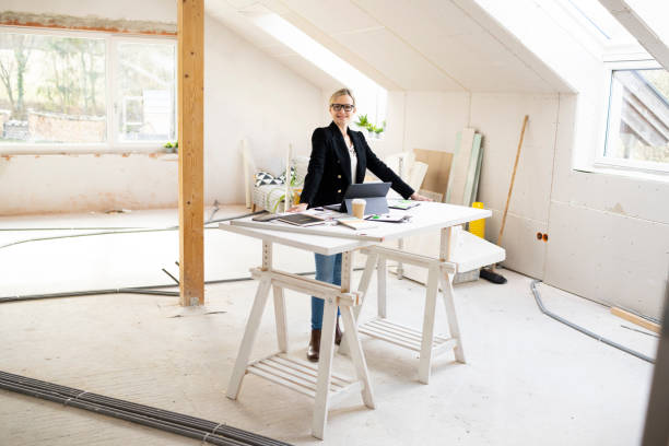istock pretty young architect working on construction site in loft and standing by high table 1383814624