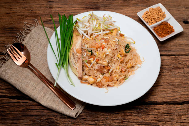 istock Fried rice noodle Pad thai has egg vegetable on wood table. 1383820729