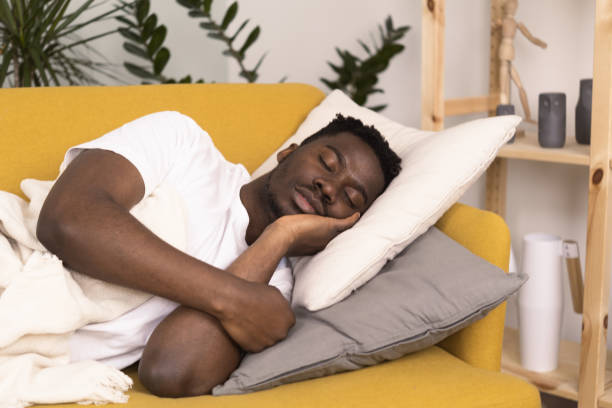 istock Young African man with a sore throat napping on the couch 1383821654