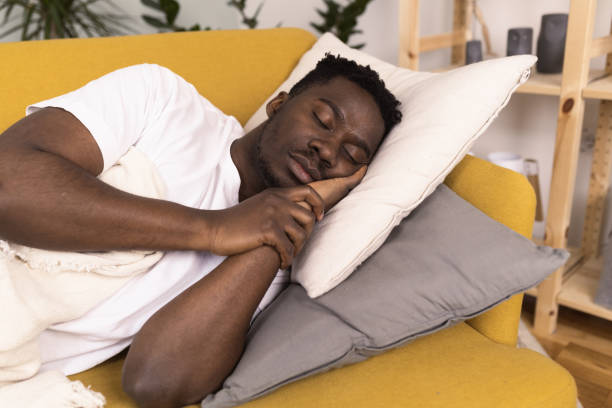 istock Young African man with a sore throat napping on the couch 1383821655